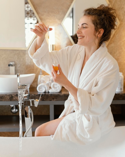 Woman in bath robe preparing bathtub