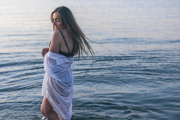 A woman in a bathing suit and a white shirt in the sea