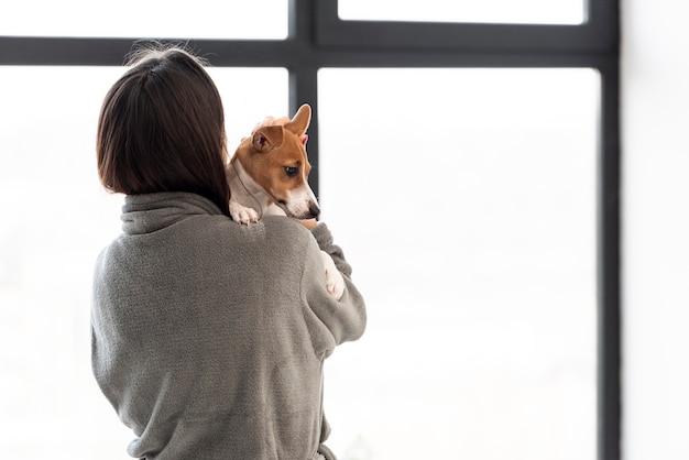 Free Photo woman in bathrobe holding her dog with copy space