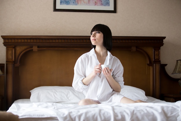 Woman in a bathrobe sitting on the bed