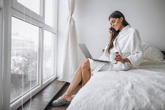 Woman in bathrobe sitting in bed 