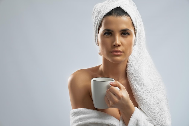 Free photo woman in bathrobe and towel holding cup