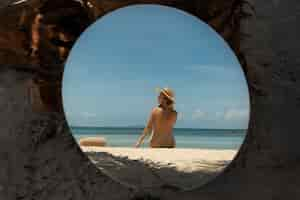 Free photo woman at the beach in summer posing with round mirror