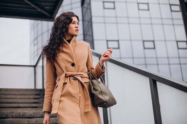 Free photo woman in beige coat walking in the city