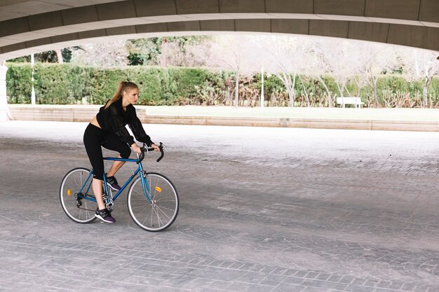 Woman on bicycle under bridge