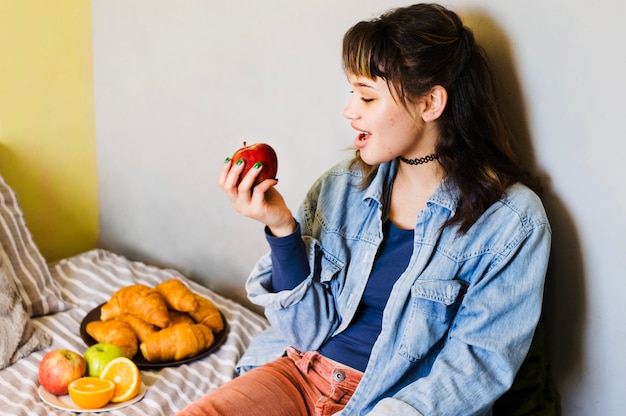 Woman biting apple on bed