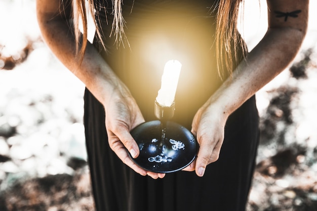 Free photo woman in black dress holding lit candle daytime in woods