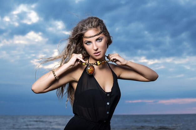 Woman in black dress posing at the seashore