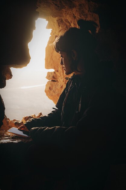 Woman in black jacket sitting on rock formation during daytime