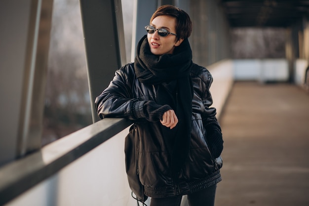 Free photo woman in black jacket walking through the bridge