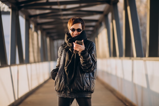 Free photo woman in black jacket walking through the bridge