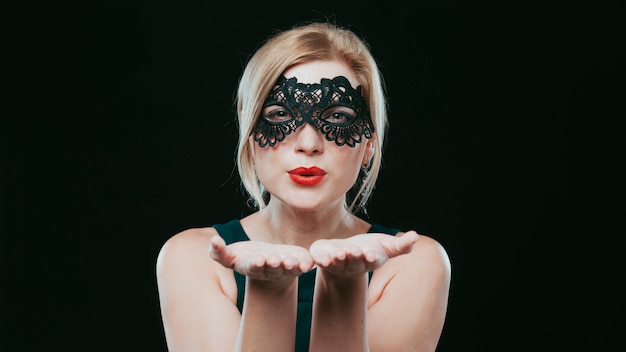 Woman in black mask blowing kiss