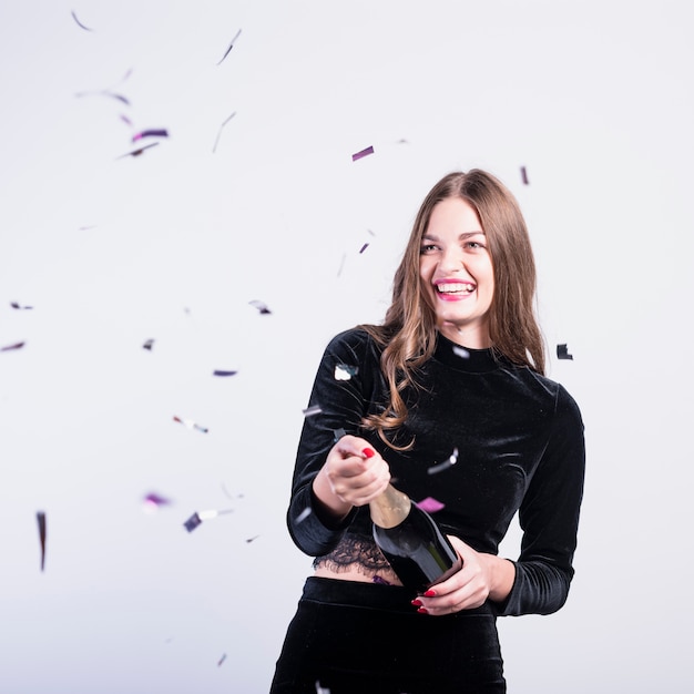 Free photo woman in black opening champagne bottle