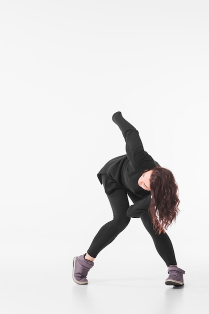 Free photo woman in black outfit dancing against white backdrop