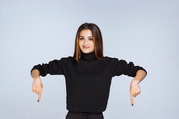 woman in black shirt pointing at downside. 