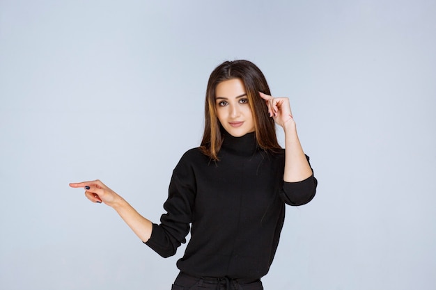 woman in black shirt pointing to the left and showing her emotions. 