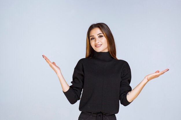 woman in black shirt pointing above. 