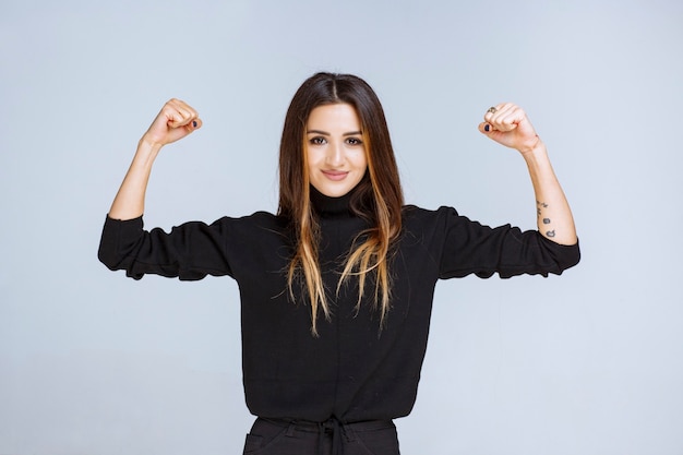 Free photo woman in black shirt showing her fists as the symbol of power.