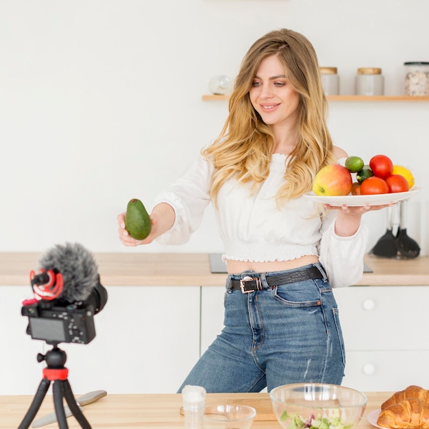 Woman blogger holding plate of fruits