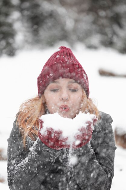 Woman blowing in a pile of snow front view