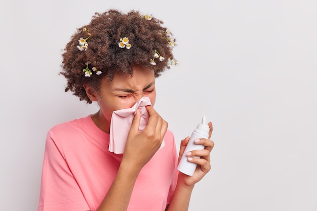 Free photo woman blows nose in tissue sprays aerosol has allergic reaction wears casual pink t shirt isolated on white