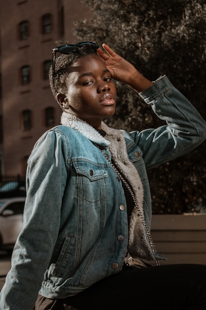 Woman in blue denim jacket sitting and posing