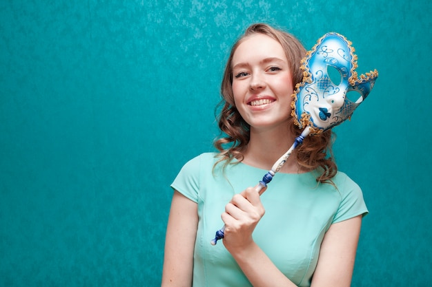 Free photo woman in blue dress holding a carnival mask