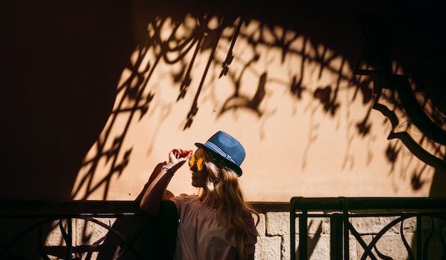 Free Photo woman in blue hat poses before a wall with shadows 