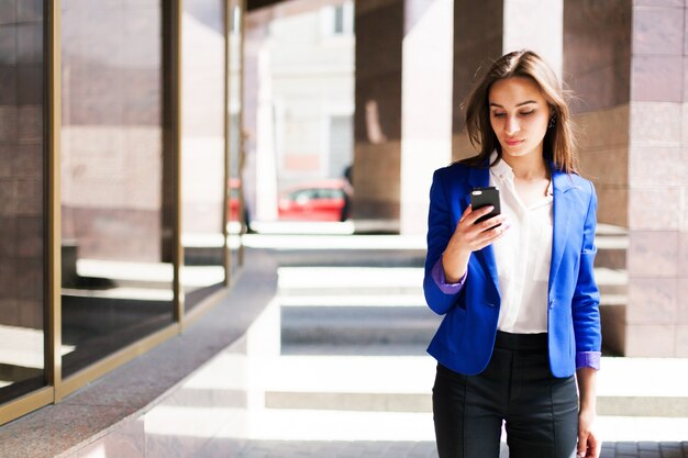 Woman in blue jacket checks her phone