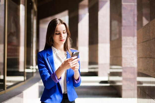 Woman in blue jacket checks her phone