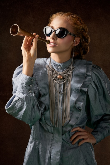 Woman in blue long sleeved dress holding trumpet 