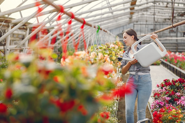 Woman in a blue shirt pours flowerpots