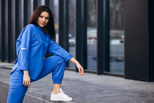 Woman in blue sports wear stretching outside the street