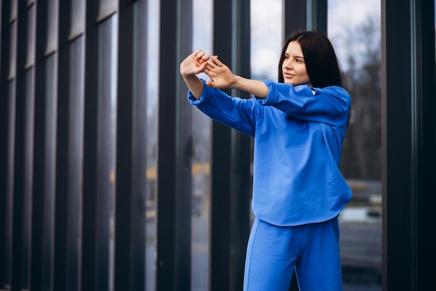 Woman in blue sports wear stretching outside the street