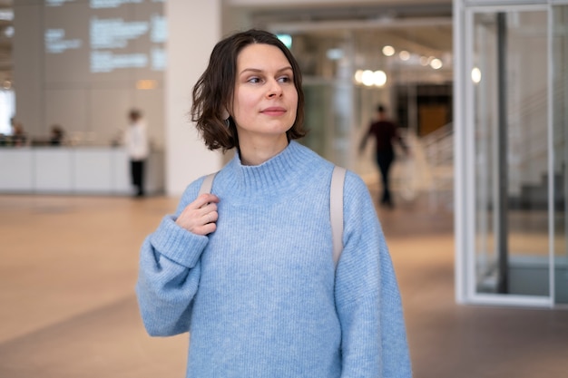 Free photo woman in blue sweater holding bag indoors