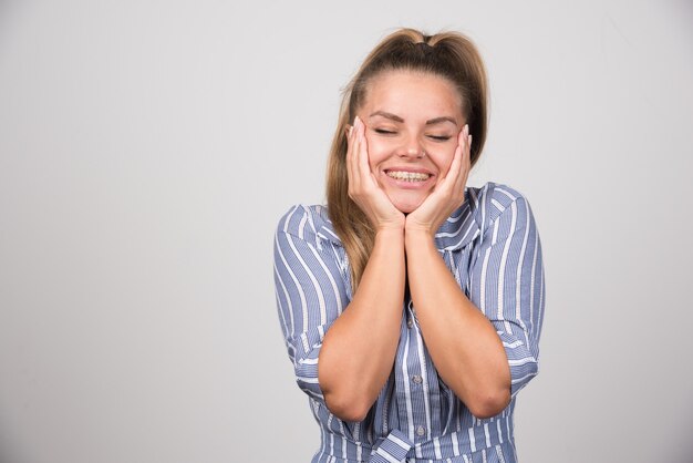 Woman in blue sweater holding her face.