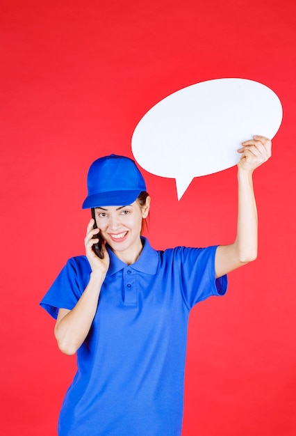 Free photo woman in blue uniform holding an ovale idea board and talking to the phone.