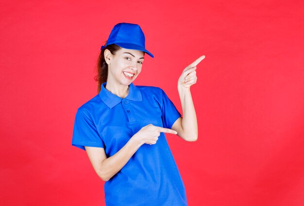 Woman in blue uniform pointing at something aside. 