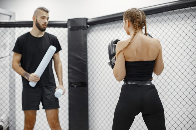 Woman boxing. Beginner in a gym. Lady in a black sportwear. Woman with coach.