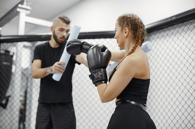 Free Photo woman boxing. beginner in a gym. lady in a black sportwear. woman with coach.