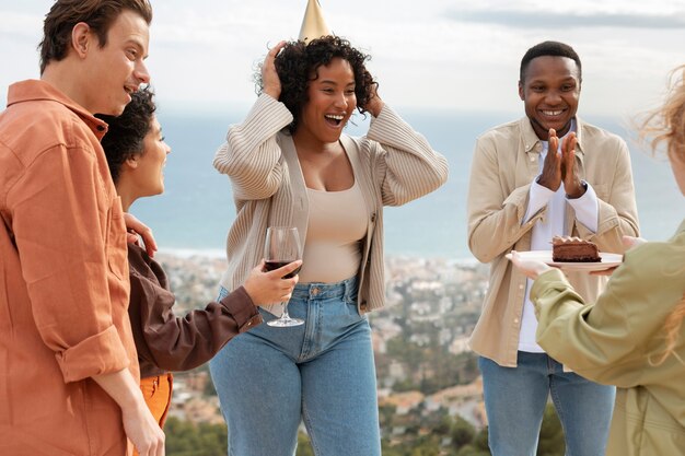 Woman bringing cake to her friends during outdoor party