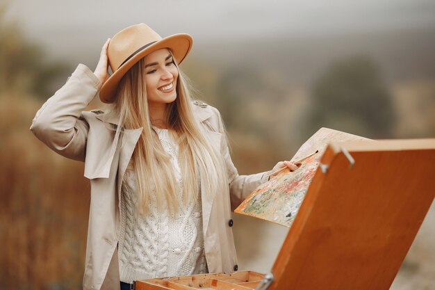 Woman in a brown coat painting in a field