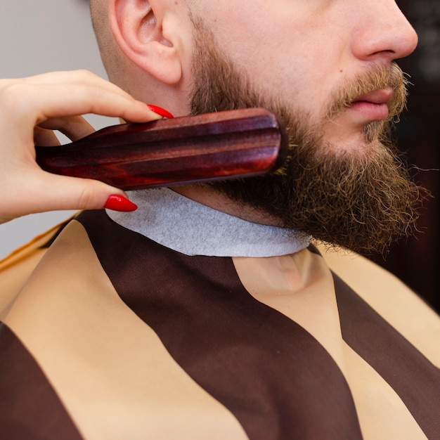 Woman brushing a man's beard close-up