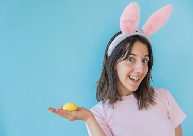 Free photo woman in bunny ears holding easter egg