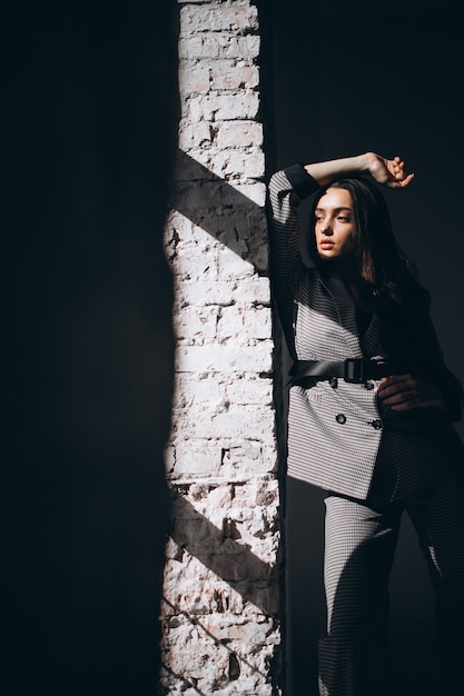 Free Photo woman in a business suit by the brick wall