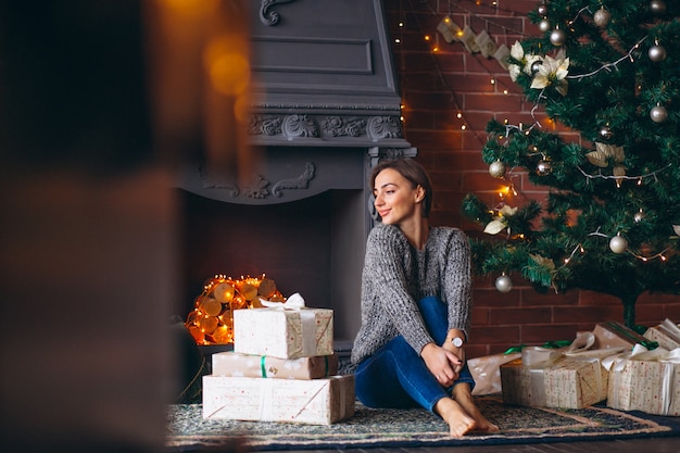 Woman by Christmas tree unpacking presents