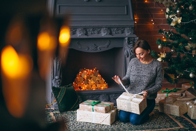 Woman by Christmas tree unpacking presents