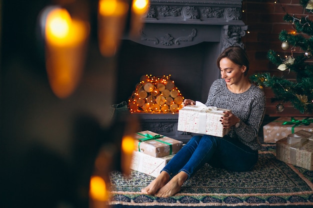 Woman by Christmas tree unpacking presents