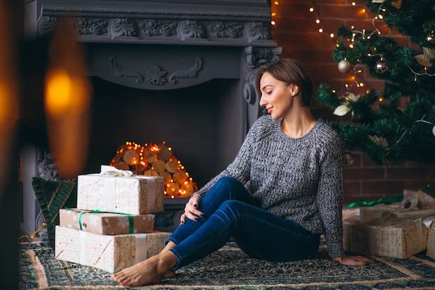 Woman by Christmas tree unpacking presents