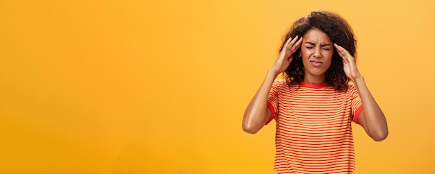 Free photo woman cannot recall important information looking intense trying concetrate under pressure feeling tensed touching temples closing eyes while thinking hard posing against orange background